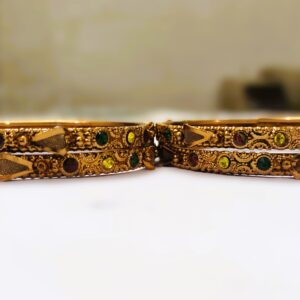 A close-up of the intricate designs and vibrant gemstones on the gold-plated bangles.