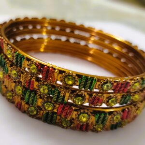 A close-up of the intricate designs and vibrant gemstones on the gold-plated bangles.