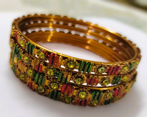 A close-up of the intricate designs and vibrant gemstones on the gold-plated bangles.