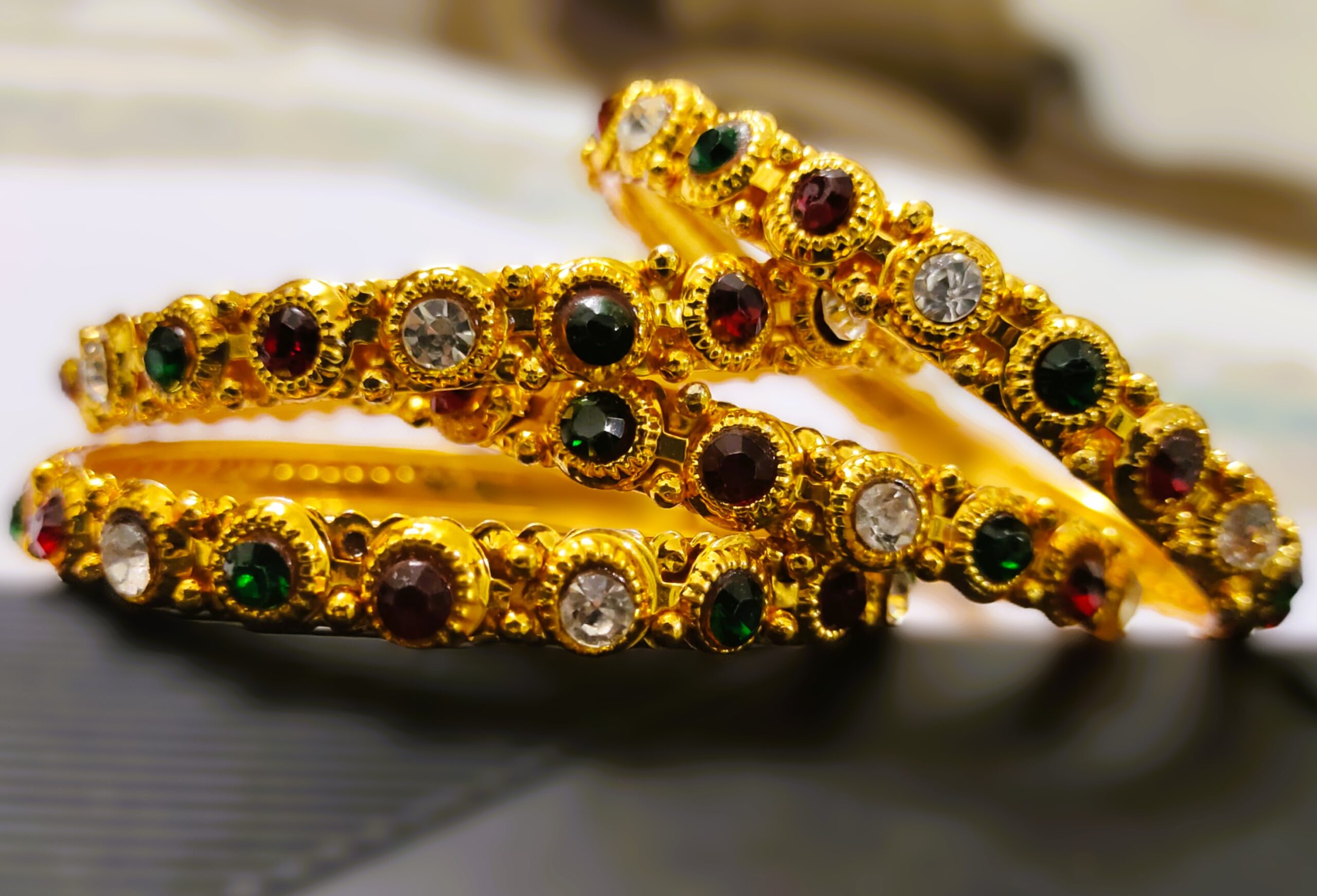 A Jaipur Royal Gemstone Bangle Set, featuring multiple gold-toned bangles adorned with sparkling gemstones.