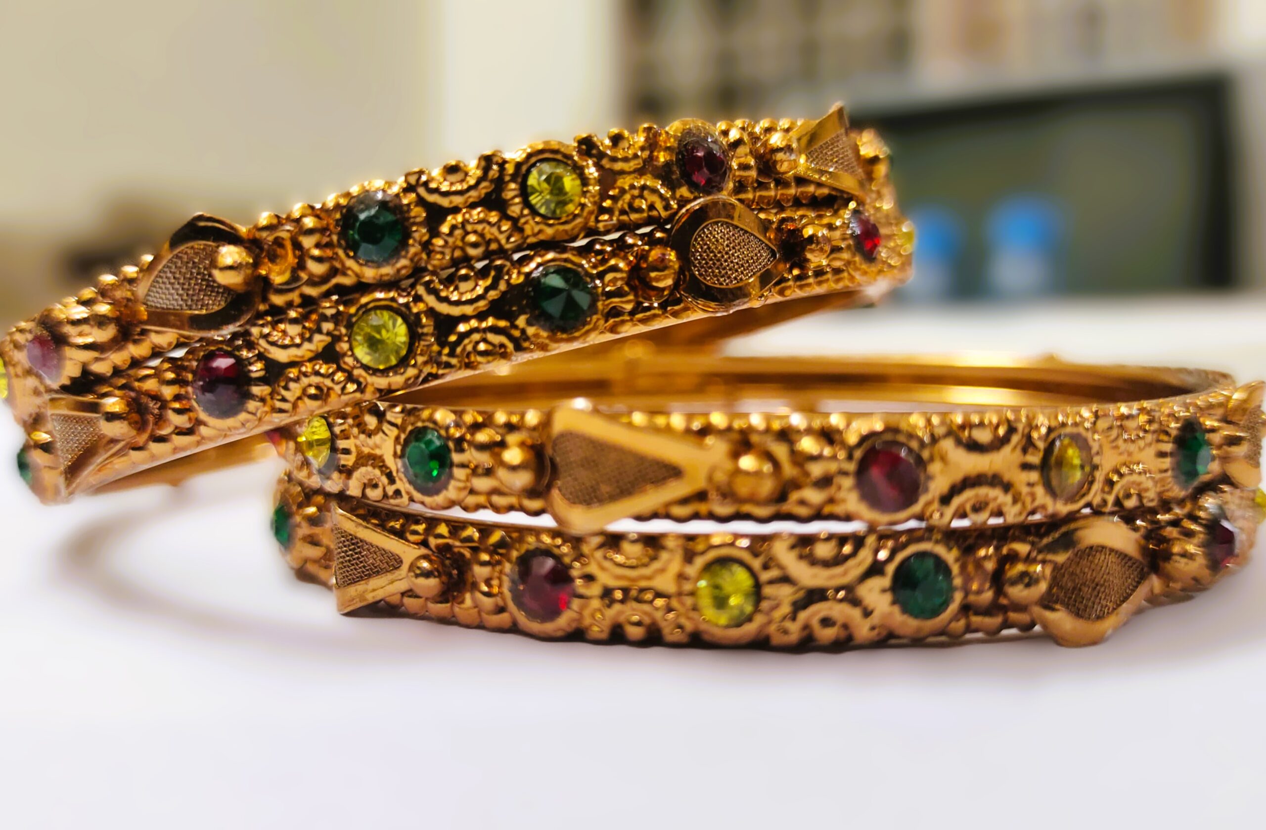 A traditional gold-plated bangle set with intricate designs and vibrant gemstones, perfect for any occasion.