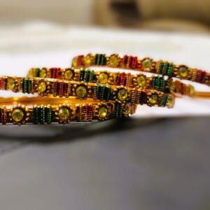 A close-up of the intricate designs and vibrant gemstones on the gold-plated bangles.