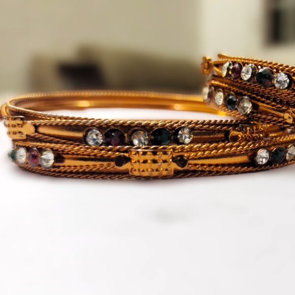 A close-up of the intricate designs and vibrant gemstones on the copper bangles.