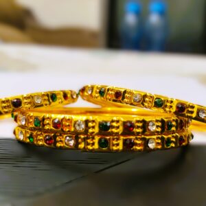 A close-up of the intricate details on a Rajputana Gemstone Bangle, showcasing the vibrant gemstones and gold-plated metalwork.