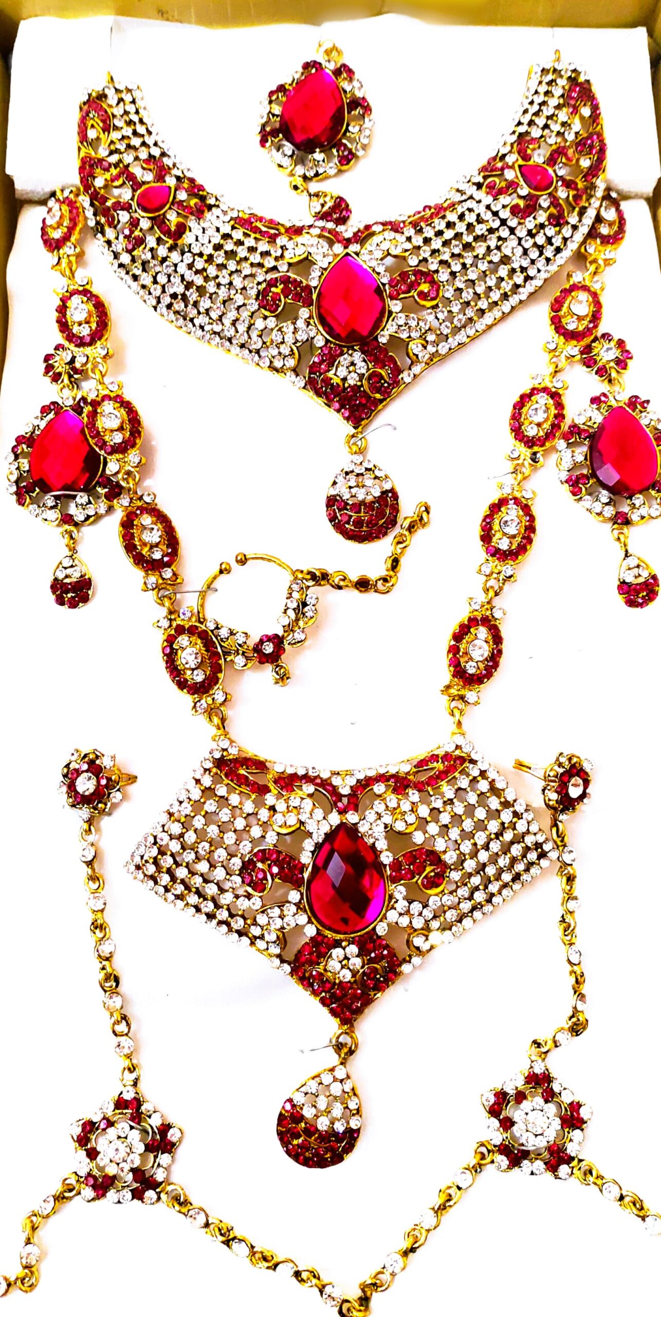 A stunning Rajasthani Bridal Jewelry Set, featuring a necklace, earrings, and a maang tika, adorned with red and white gemstones.