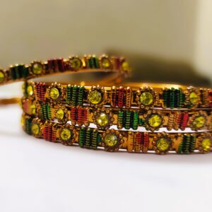 A close-up of the intricate designs and vibrant gemstones on the gold-plated bangles.