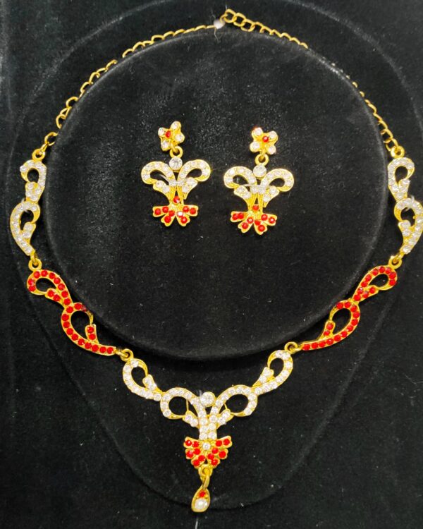 A stunning Jaipur Crimson Rhapsody Bridal Jewelry Set, featuring a necklace, earrings, maang tika, and choker adorned with red and white stones.