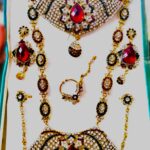 A stunning Rajasthani Royal Crimson and Ivory Bridal Jewelry Set, featuring a necklace, earrings, maang tika, choker, and other pieces, adorned with red and white gemstones.