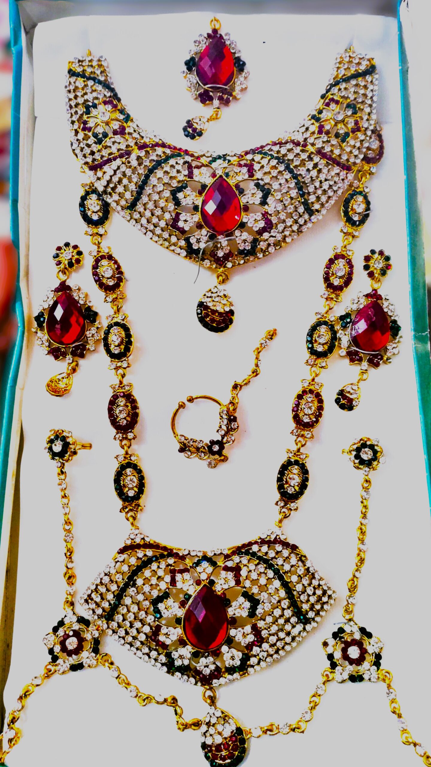 A stunning Rajasthani Royal Crimson and Ivory Bridal Jewelry Set, featuring a necklace, earrings, maang tika, choker, and other pieces, adorned with red and white gemstones.