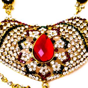 A close-up of the intricate details on the Rajasthani Bridal Necklace, showcasing the red and white gemstones and gold-plated metalwork.