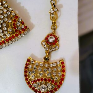 A close-up of the Rajasthani Royal Gold-Plated Bridal Earrings, showcasing the red and white gemstones and gold-plated metalwork.