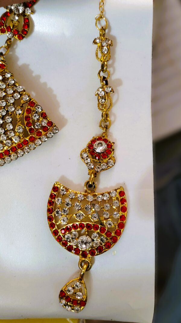 A close-up of the Rajasthani Royal Gold-Plated Bridal Earrings, showcasing the red and white gemstones and gold-plated metalwork.