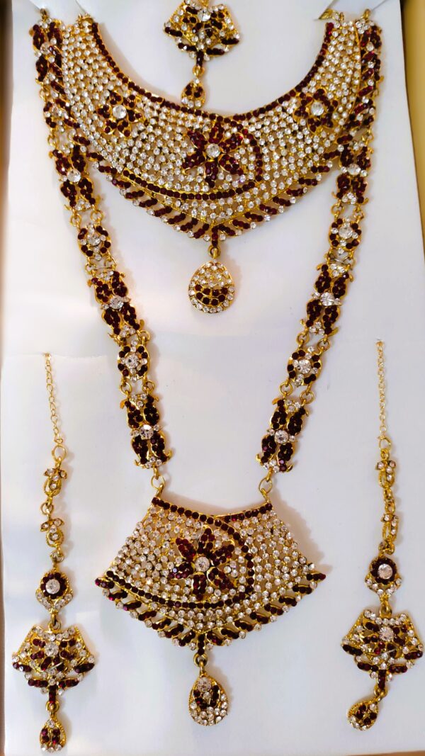 A traditional bridal jewelry set with necklace, earrings, maang tika, and choker, adorned with Kundan and American diamond stones.