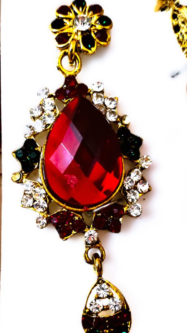 A close-up of the Rajasthani Gold-Plated Bridal Earrings, showcasing the red and white gemstones and gold-plated metalwork.