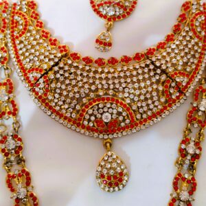 A close-up of the intricate details on the Rajasthani Royal Gold-Plated Bridal Necklace, showcasing the red and white gemstones and gold-plated metalwork.