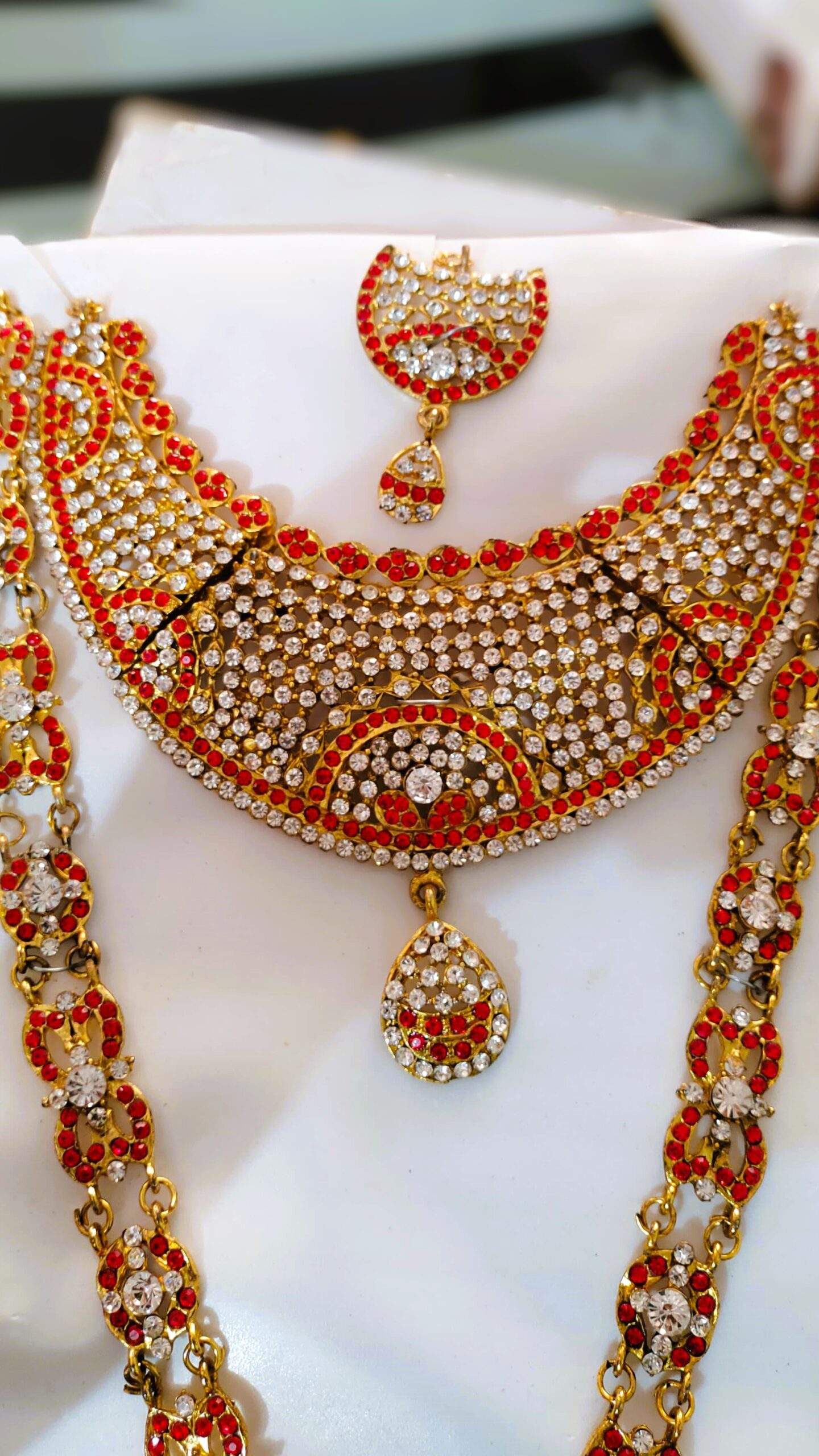 A close-up of the intricate details on the Rajasthani Royal Gold-Plated Bridal Necklace, showcasing the red and white gemstones and gold-plated metalwork.