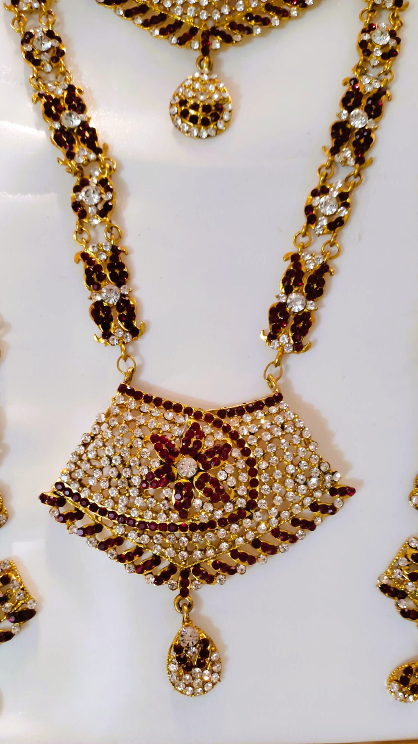 A close-up of the intricate details on the Rajasthani Royal Gold-Plated Bridal Necklace, showcasing the crimson and ivory gemstones and gold-plated metalwork.