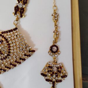 A close-up of the Rajasthani Royal Gold-Plated Bridal Earrings, showcasing the crimson and ivory gemstones and gold-plated metalwork.