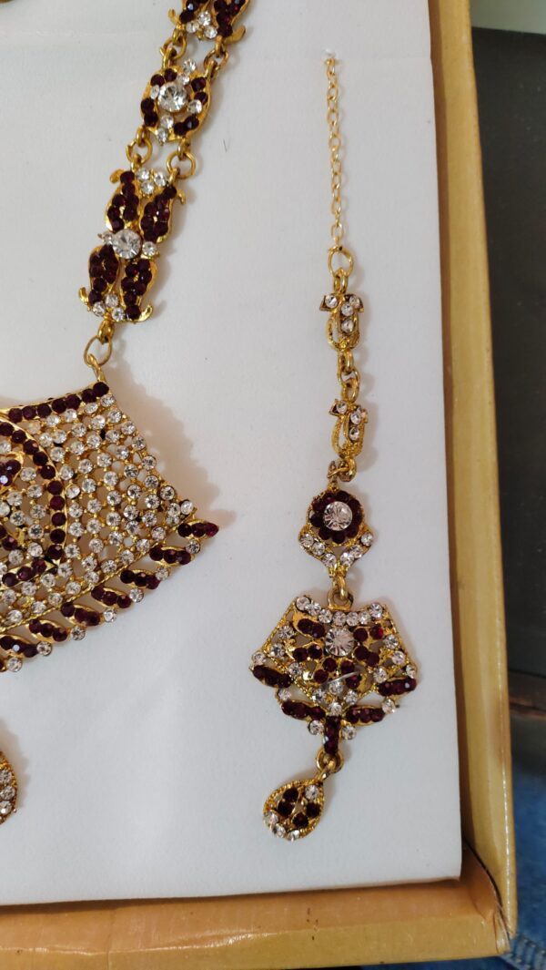 A close-up of the Rajasthani Royal Gold-Plated Bridal Earrings, showcasing the crimson and ivory gemstones and gold-plated metalwork.