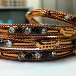 A traditional copper bangle set with intricate designs and vibrant gemstones, perfect for any occasion.