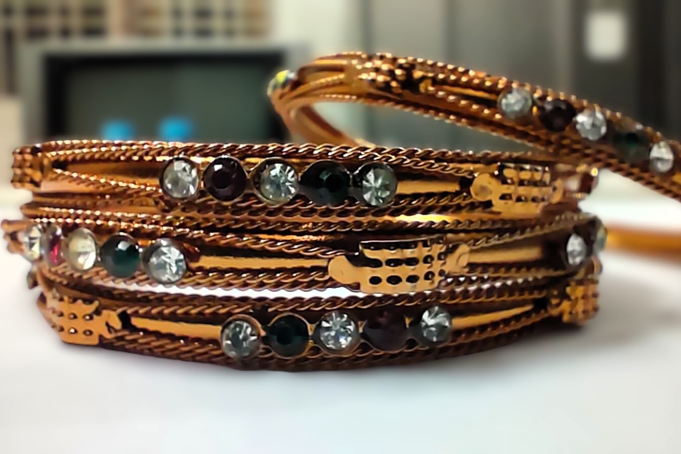 A traditional copper bangle set with intricate designs and vibrant gemstones, perfect for any occasion.