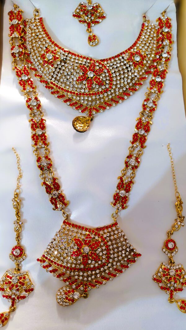 A stunning Rajasthani Royal Crimson and Ivory Bridal Jewelry Set, featuring a necklace, earrings, and a maang tika, adorned with intricate designs and vibrant gemstones.