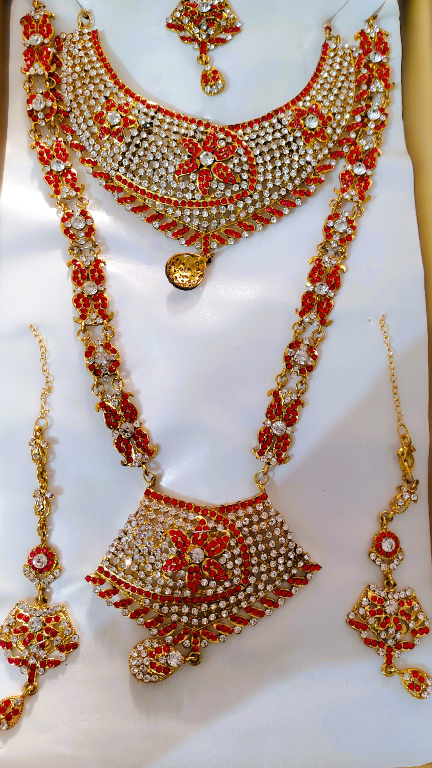 A Rajasthani Royal Bridal Jewelry Set with necklace, earrings, maang tika, and choker, adorned with Kundan and American diamond stones.