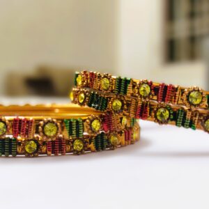 A close-up of the intricate designs and vibrant gemstones on the gold-plated bangles.