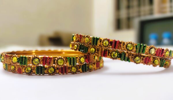 A close-up of the intricate designs and vibrant gemstones on the gold-plated bangles.