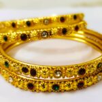 An Anaka Traditional Gold-Plated Bangle Set with intricate designs and vibrant ruby, pink, and green gemstones, perfect for any occasion.