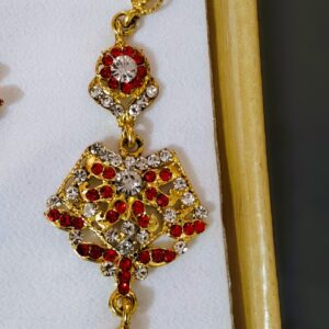 A close-up of the Rajasthani Royal Crimson and Ivory Bridal Earrings, showcasing the crimson and ivory gemstones and gold-plated metalwork.