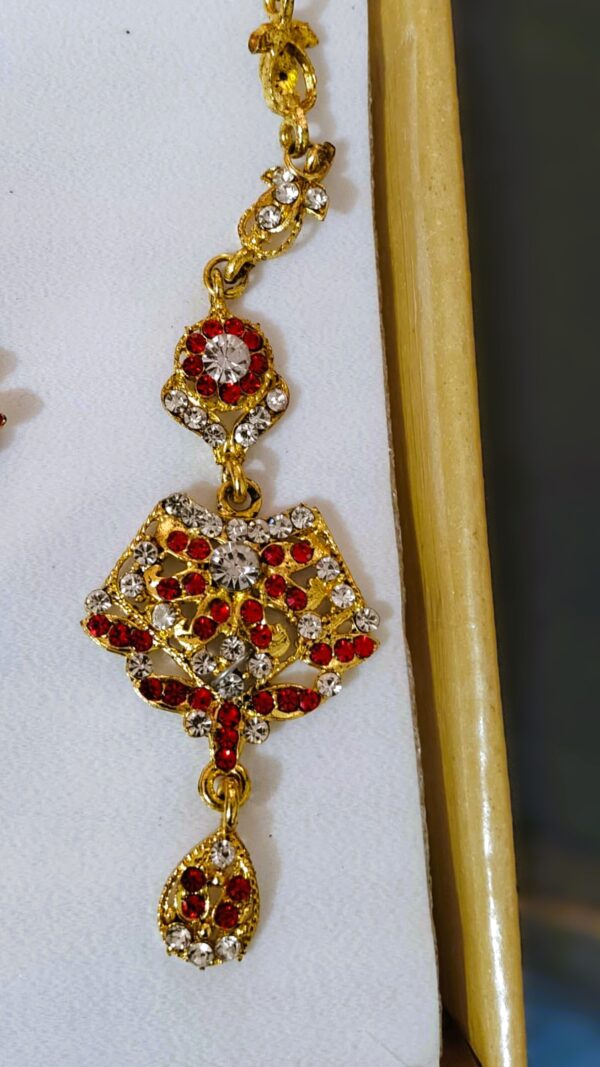 A close-up of the Rajasthani Royal Crimson and Ivory Bridal Earrings, showcasing the crimson and ivory gemstones and gold-plated metalwork.